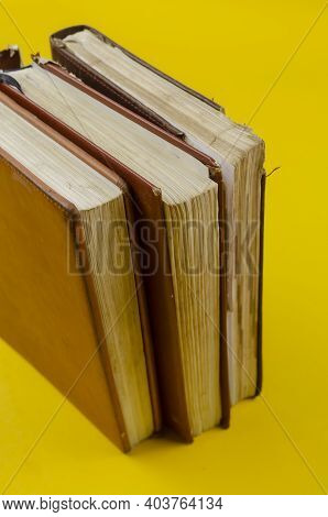 Three Old Dailies Standing On Endpaper On Yellow Background. The Diaries Have Worn Pages.