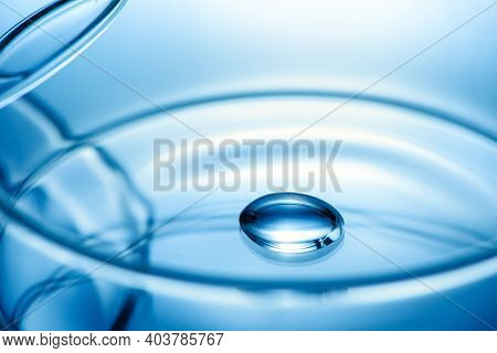 Clean Glass Petri Dish With Liquid Drop Inside Over Blue Light Background