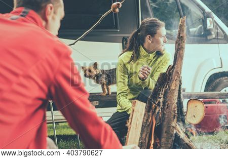 Caucasian Couple In Their 30s Burning Campfire While Staying Overnight In The Rv Park. Modern Camper