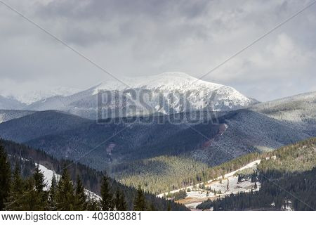 Snowy Treeless Mountain Range Partly In Clouds And Mountain Slopes Covered With Fir Forest In The Ca