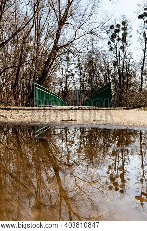 Long Concrete Bridge Over River With Green Metal Railing Reflected In Small Puddle