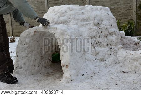 Man, Dad, Builds A Children\'s Igloo House Out Of Snow Which Is Very Little Is Dirty With Grass Clay