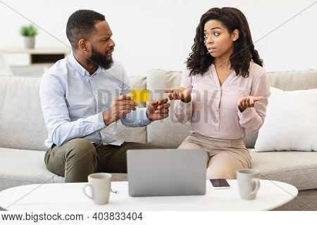 Spender. Angry Black Husband Holding Credit Card, Blaming His Wife For Overspending And Wasting Too 