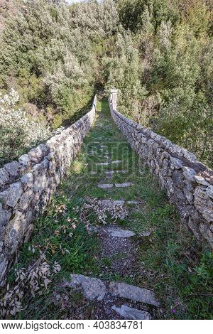 Old Stone Bridge Leading To Small Mountain Village With A Few Remaining Residents