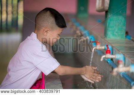 Asian Little Child Boy Washing Hands At The School. A Combined Sink That Can Wash Multiple People At