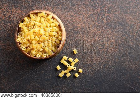 Ditalini Soup Pasta In Wooden Bowl On Brown Table. View From Above. Copy Space.