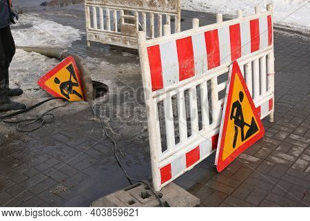 Road Works Sign. The Municipal Service Removes The Blockage In The Sewer Hatch. Severe Winter Frosts