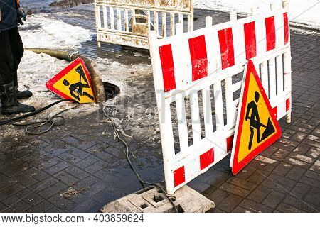 Road Works Sign. The Municipal Service Removes The Blockage In The Sewer Hatch. Severe Winter Frosts