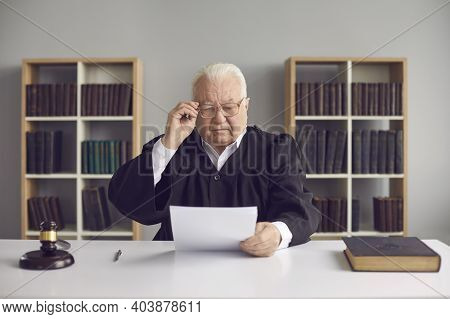 Senior Man Professional Judge Learning Details Of Case On Paper During Court