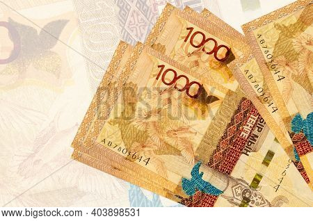 1000 Kazakhstani Tenge Bills Lies In Stack On Background Of Big Semi-transparent Banknote. Abstract 
