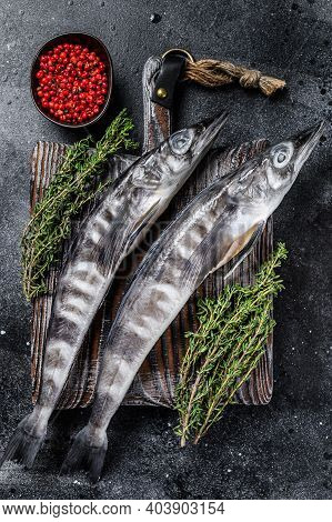 Raw Icefish On A Wooden Cutting Board. Black Background. Top View