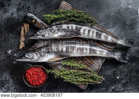 Raw Icefish On A Wooden Cutting Board. Black Background. Top View