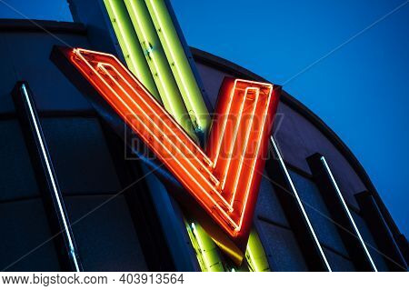 Vintage Neon Light Tubes Forming Letter V On The Metallic Roof Top With Dusk Blue Warm Color Skyligh