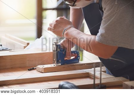 Entrepreneur  Woodwork Holding A Tacker To Assemble The Wood Pieces As The Customer Ordered