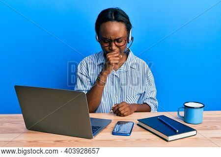 Young african woman wearing call center agent headset feeling unwell and coughing as symptom for cold or bronchitis. health care concept. 