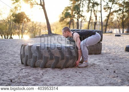 Strong Man Training Workout Lifting Large Tire Outdoor Diy Gym. Sportive Young Adult Caucasian Guy F