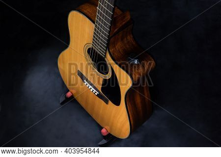 Top View On Body Of Classic Yellow Acoustic Guitar With Steel Strings On Black Isolated Background