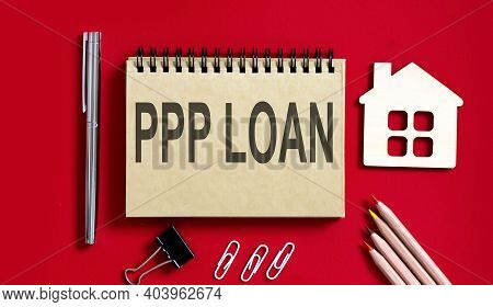 Ppp Loan Text Written On Notebook With Pencils And Office Tools And Model Wooden House