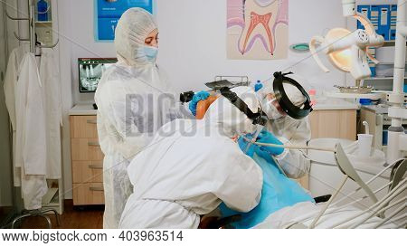 Little Patient In Ppe Suit Lying On Chair With Open Mouth During Dental Examination In Coronavirus P