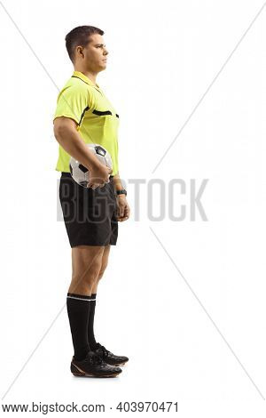 Full length profile shot of a footall referee holding a ball under arm isolated on white background