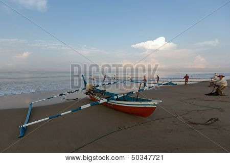 PADANG - AUGUST 25: Fishermen work as a team pull in the fishing nets from the sea in Padang, West Sumatera, Indonesia on August 25, 2013. Resources from the sea is a major revenue earner.  
