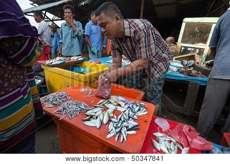 PADANG - AUGUST 25: A fishmonger attends to a customer in a stall at a village market in Padang, West Sumatera, Indonesia on August 25, 2013. Resources from the sea is a major revenue earner.  