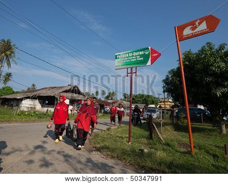 PADANG - AUGUST 25: Villagers return home after marketing in Padang, Sumatera, Indonesia on August 25, 2013. The signage shows a tsunami evacuation path which is a real and present danger here. 