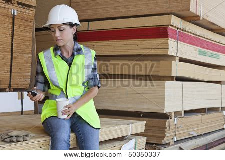Female industrial worker taking break from work at timber yard