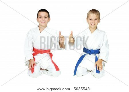 Boys athletes sit in a ritual pose karate and point the finger super