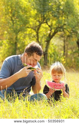 Father And Young Daughter Eat Watermelon In Nature