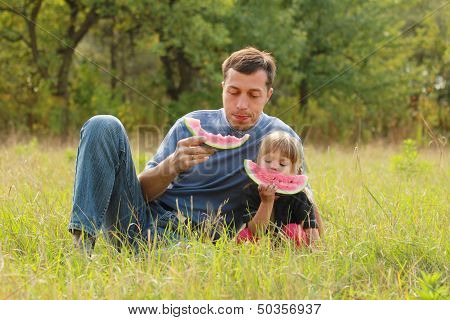 Father And Young Daughter Eat Watermelon In Nature