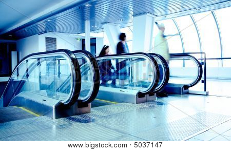 Persone in piedi sulla scala mobile nel moderno Business Center