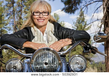 Senior woman leaning on motorbike handlebars