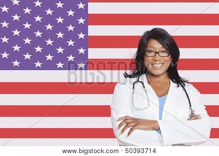 Portrait of confident mixed race female surgeon over American flag