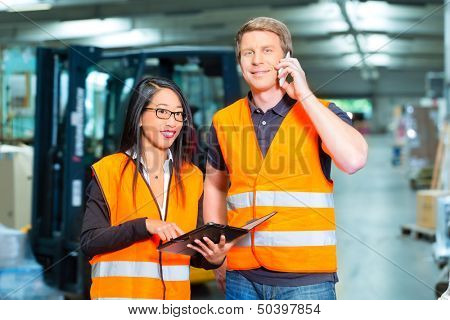Logistics Teamwork - Worker or warehouseman and his female coworker with tablet computer at warehouse of freight forwarding company