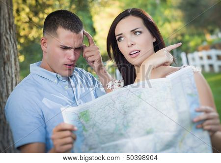 Lost and Confused Mixed Race Couple Looking Over A Map Outside Together.