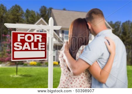 For Sale Real Estate Sign and Affectionate Military Couple Looking at Nice New House.