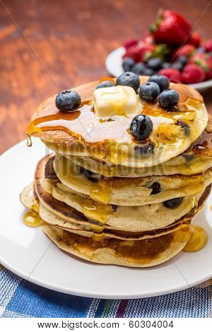 Big Pile of American Blueberry Pancakes with Berries and Maple Syrup