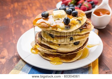 Big Pile of American Blueberry Pancakes with Berries and Maple Syrup