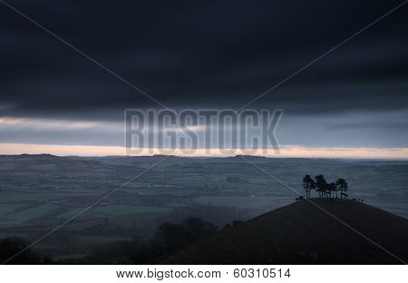 Beautiful Sunrise Dawn Landscape Of Hills Overlooking Brightly Lit Town In Valley Below