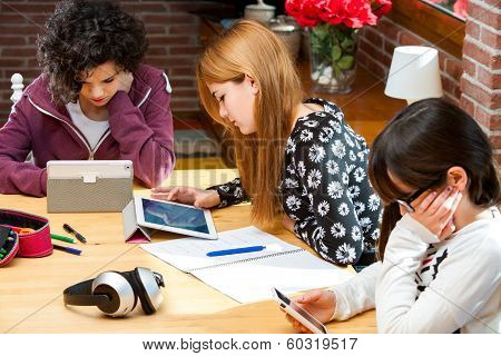Three Students Working On Digital Devices.