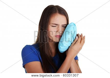 Teen woman pressing her bruised cheek with a painful expression as if she's having a terrible tooth ache. 