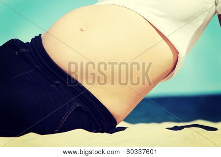 Beautiful pregnant woman relaxing at the beach