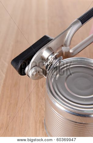 Can piercer with canned on wooden background