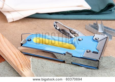 Construction stapler with fabric and staples on cork board close up