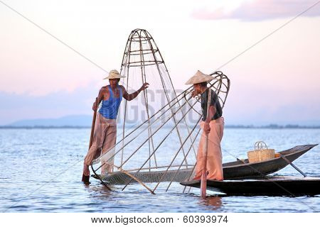 INLE LAKE, MYANMAR  DECEMBER 12, 2013: Fishermen at Inle Lake, Shan State, Myanmar Intha people possess the leg-rowing style and the unique coop-like fishing equipment
