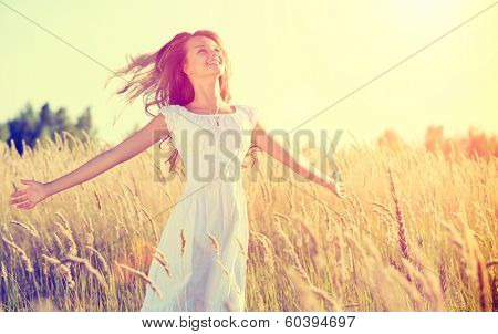Beauty Girl Outdoors enjoying nature. Beautiful Teenage Model girl in white dress running on the Spring Field, Sun Light. Glow Sun. Free Happy Woman. Toned in warm colors. 