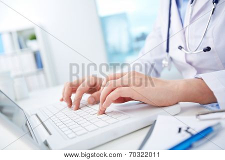 Close-up of hands of a nurse typing on laptop