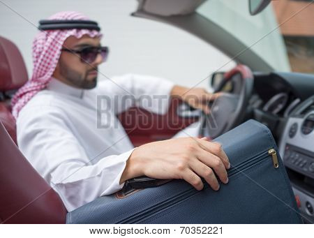 Arabic young businessman driving car and holding briefcase