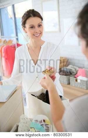 Customer in clothing store giving credit card to seller